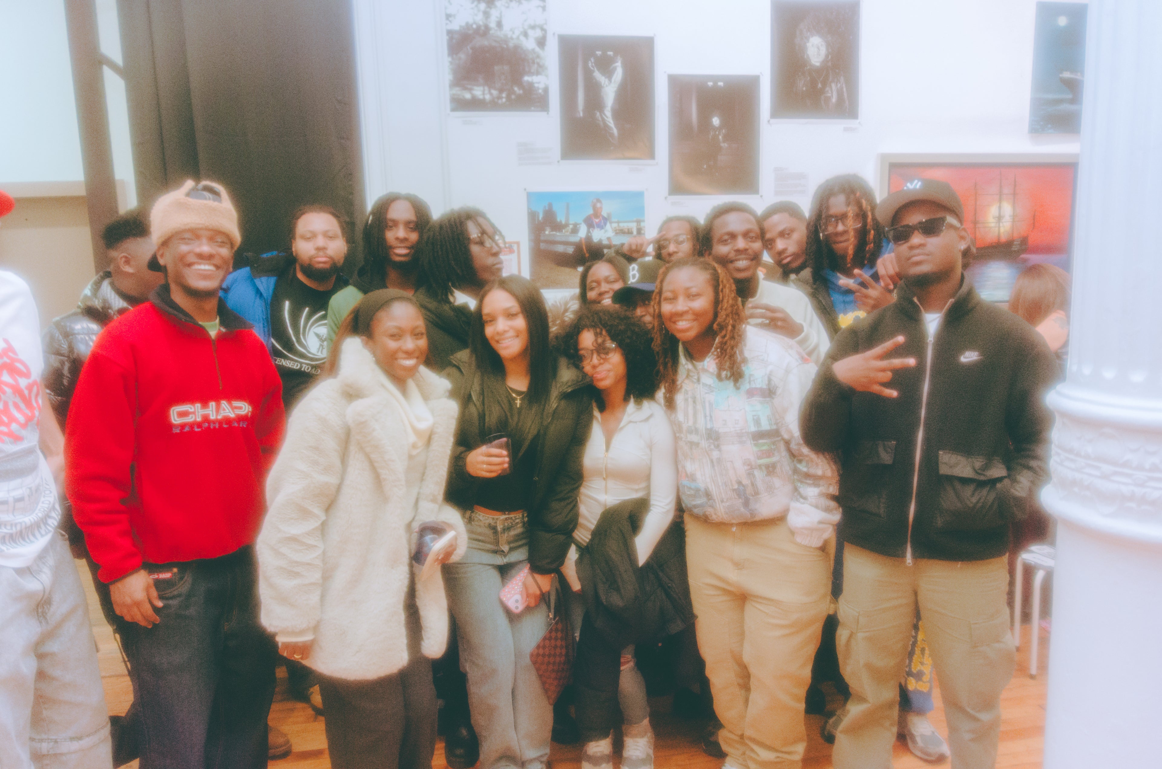 Group of people posing together in a room with framed pictures on the wall.